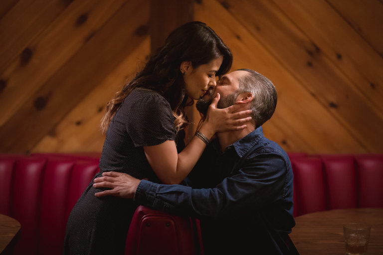 couple kissing in red booth at dive bar captain keno's encinitas engagement session